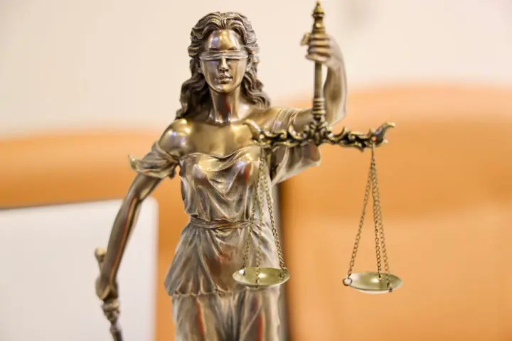Estatueta de metal da deusa da justiça, de olhos vendados, segurando a balança.